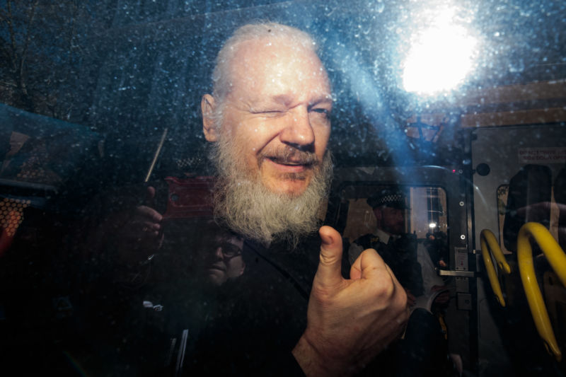 Julian Assange gestures to the media from a police vehicle on his arrival at court on April 11, 2019 in London.