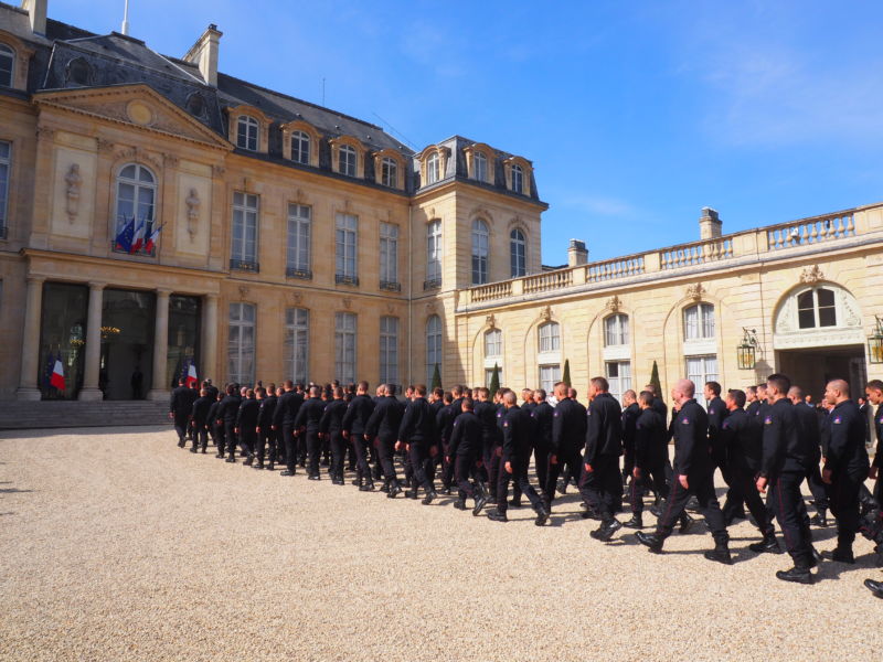 Rows of people in uniform march into a palace.