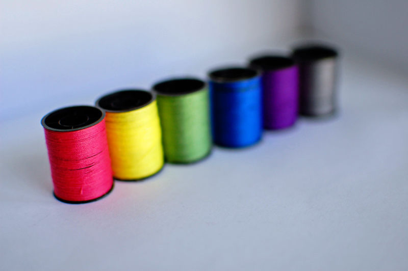 Different-colored rolls of thread are lined next to each other.