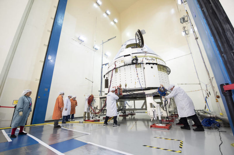 Technicians at the Boeing Space Environment Test Facility in El Segundo, California, position Starliner inside the acoustics test chamber.