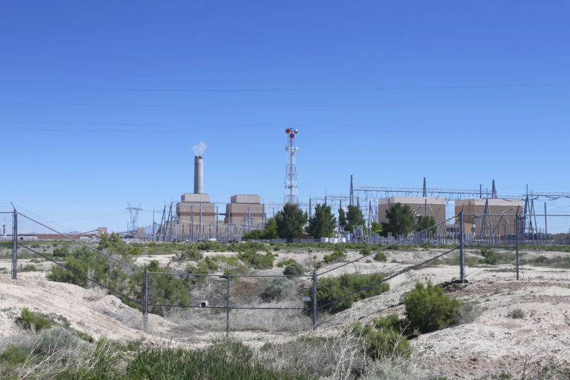 Coal-fired power plant beyond a fence.