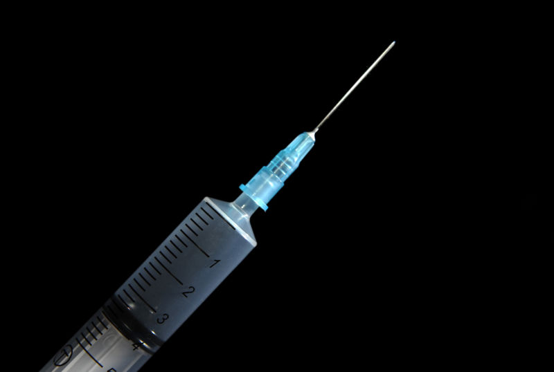 Close-up photo of a hypodermic needle on a black background.