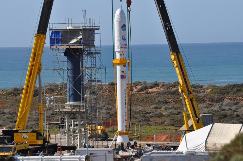 At Vandenberg Air Force Base in 2009, two cranes have raised NASA's Orbiting Carbon Observatory, or OCO, spacecraft to vertical. OCO would later be lifted and attached to the waiting Stage 0 motor of the Taurus XL launch vehicle in the tower. 