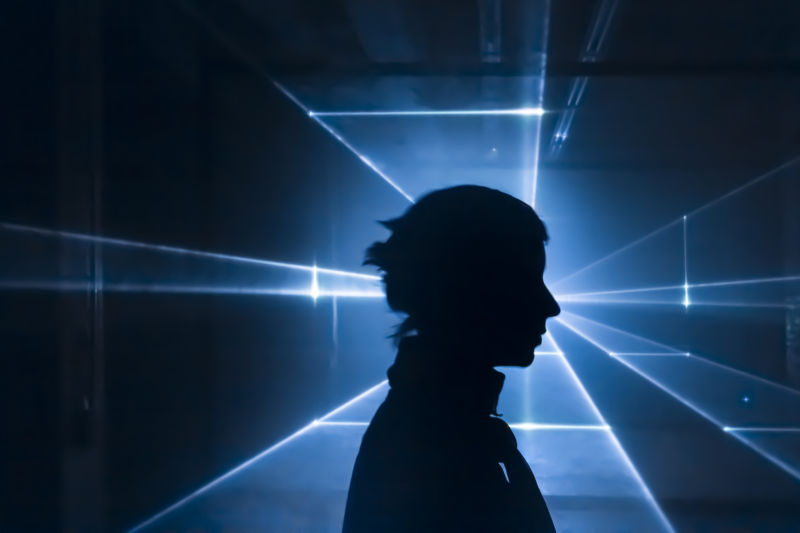 Silhouette of person in front of laser-light projection.