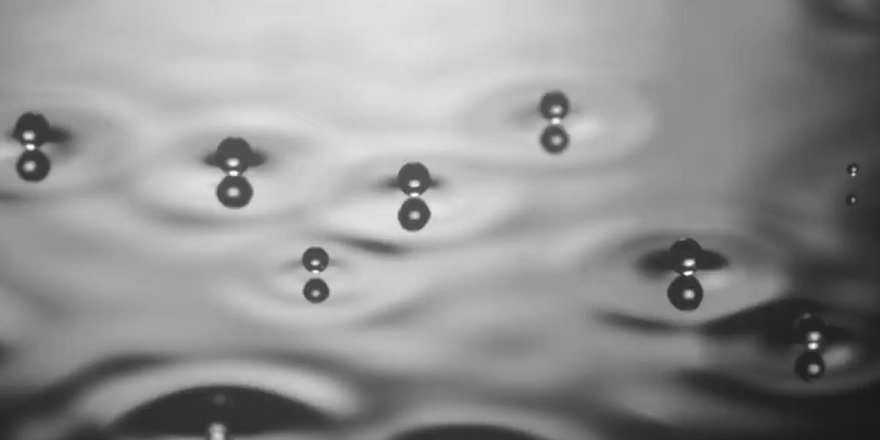 Black and white image of bubbles poised above a surface.