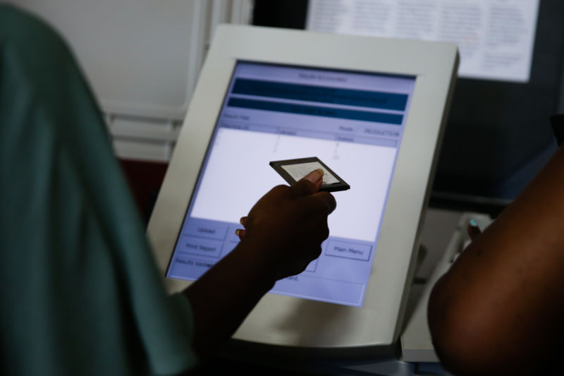 An election official holds an electronic voting machine memory card following the Georgia primary runoff elections at a polling location in Atlanta, Georgia, US, on Tuesday, July 24, 2018.