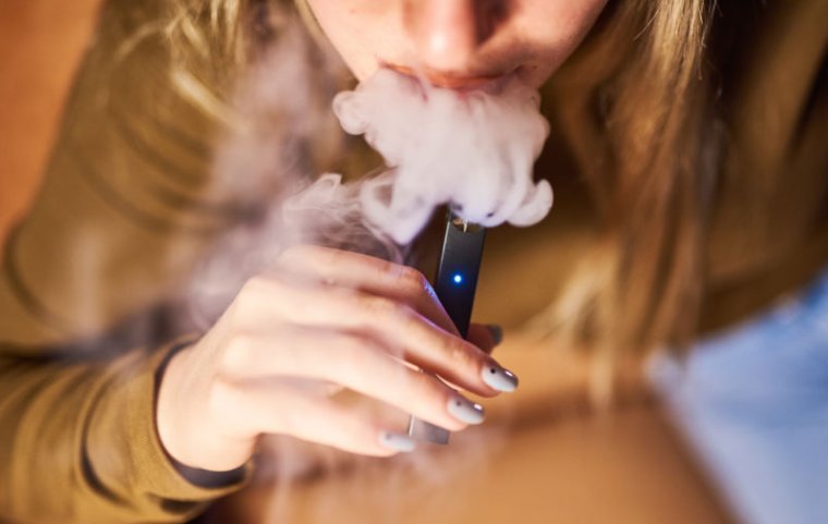 A person smokes a Juul Labs Inc. e-cigarette.