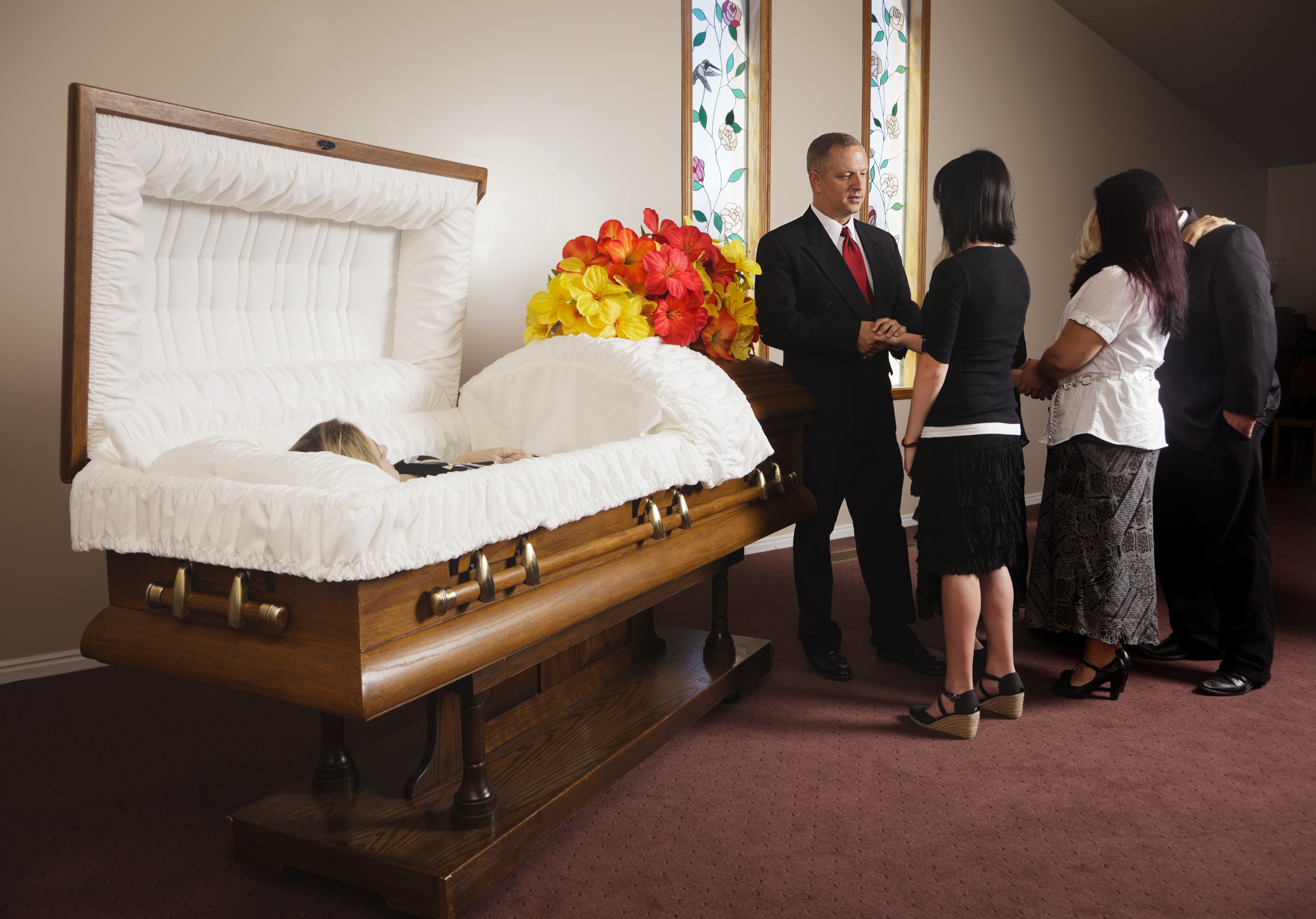 A receiving line of guests next to the casket at a funeral in a funeral hom...