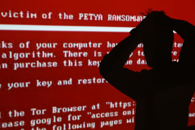 RYAZAN, RUSSIA - JUNE 28, 2017: The silhouette of a young man against a red background with a projected message related to the Petya ransomware; on 27 June 2017 a variant of the Petya ransomware virus hit computers of companies in Russia, Ukraine, and other countries in a cyber attack. Alexander Ryumin/TAS (Photo by Alexander Ryumin TASS via Getty Images)
