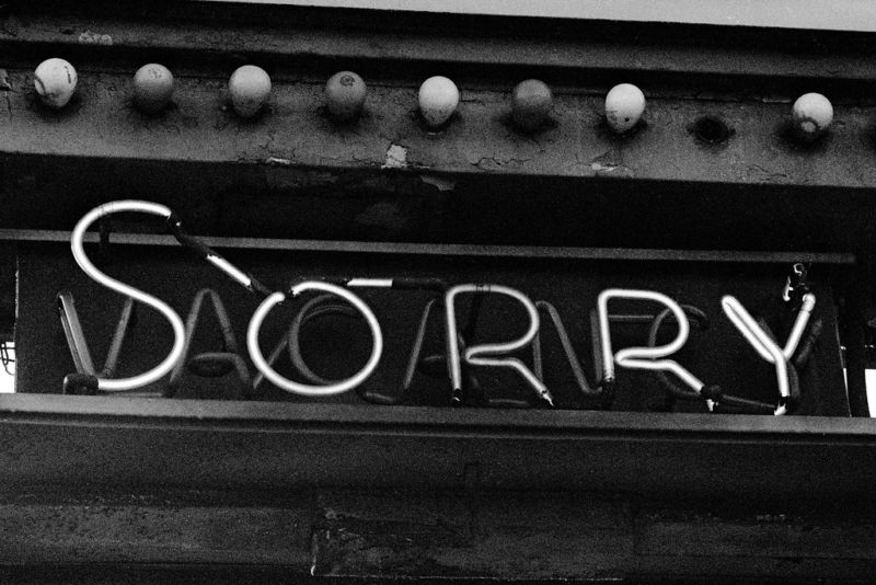 Black and white photo of neon sign that says SORRY.