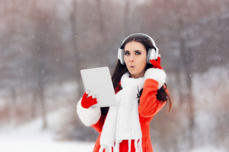 Stock photo of young woman wearing headphones in snow.