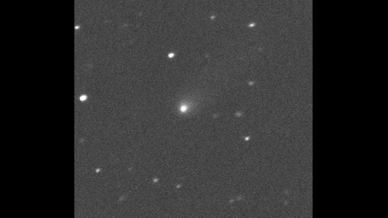 Image of a fuzzy white object on a dark grey field specked with stars.