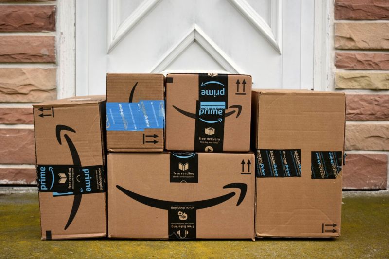 A pile of Amazon boxes in front of the door of a house.