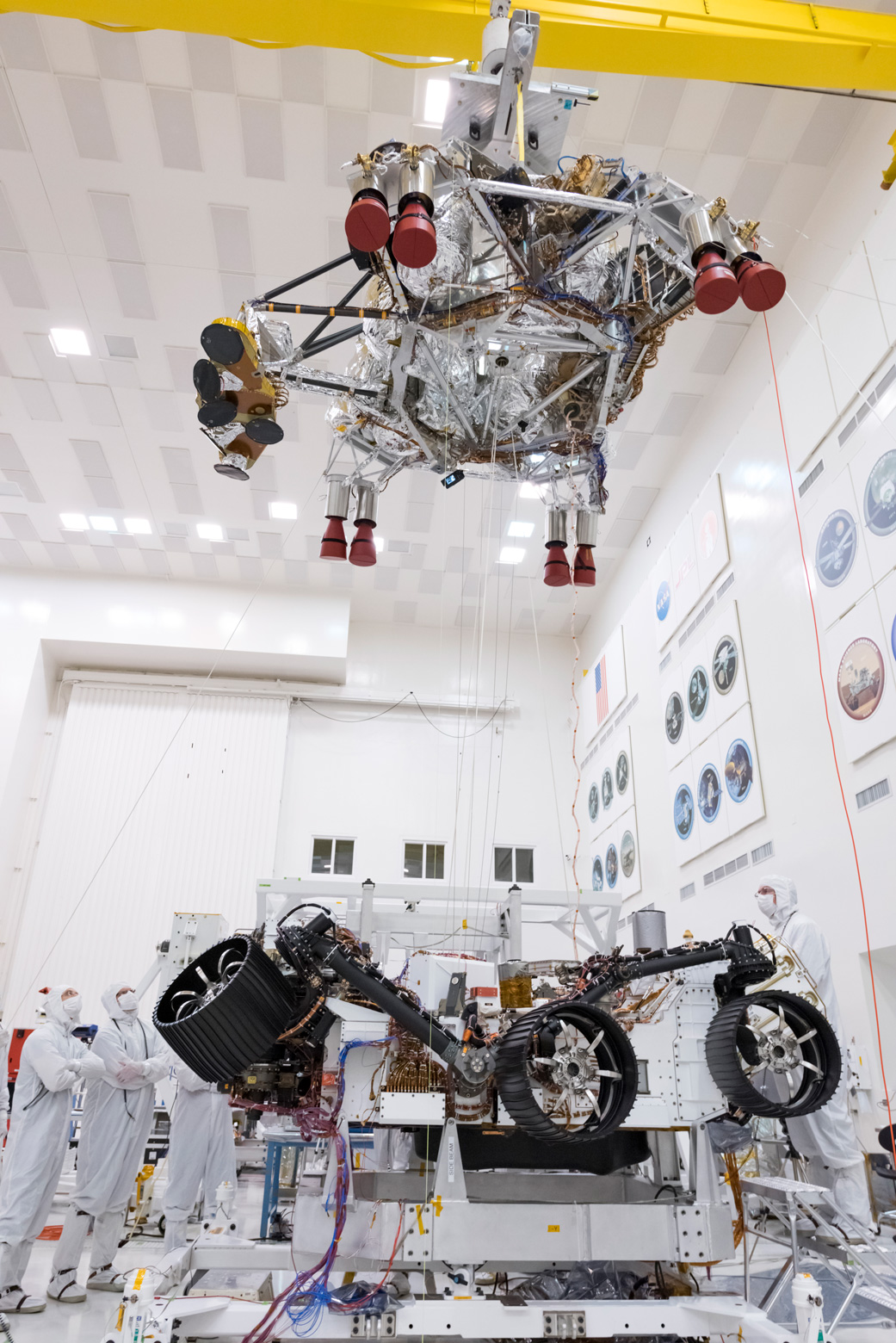 On Sept. 28, 2019, engineers and technicians working on the Mars 2020 spacecraft at NASA's Jet Propulsion Laboratory in Pasadena, California, look on as a crane lifts the rocket-powered descent stage away from the rover after a test.