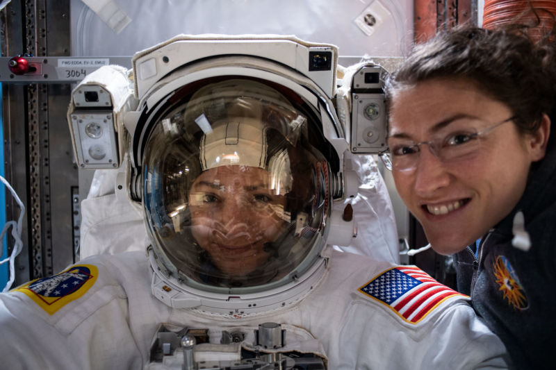 NASA astronaut Christina Koch (right) poses for a portrait with fellow Expedition 61 Flight Engineer Jessica Meir, who is inside a US spacesuit for a fit check.