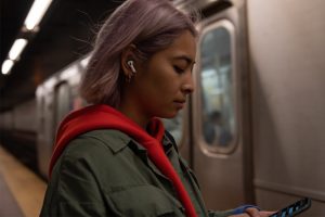 Promotional image of hip woman using Airpods on subway.