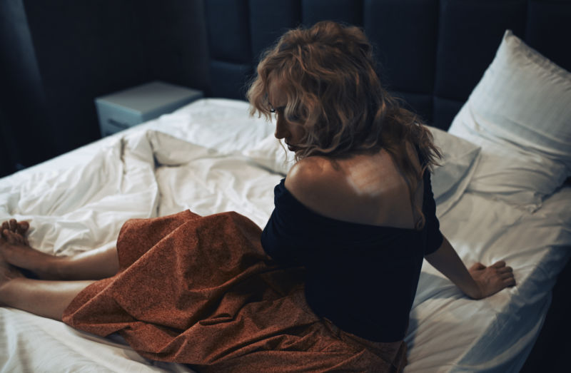 Pensive sad woman sitting on a bed