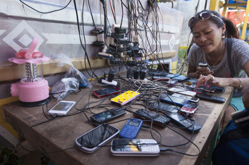 Cellphones of all design clutter a table in order to share a single cluttered power outlet.