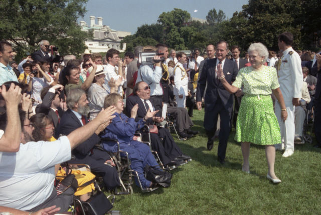 Back in 1990, President George H.W. Bush and Barbara Bush receive applause by some of the 2,000 people from major disability groups who gathered to witness the signing of the Americans with Disabilities Act (ADA). (How times have changed—take a gander at that video camera!)