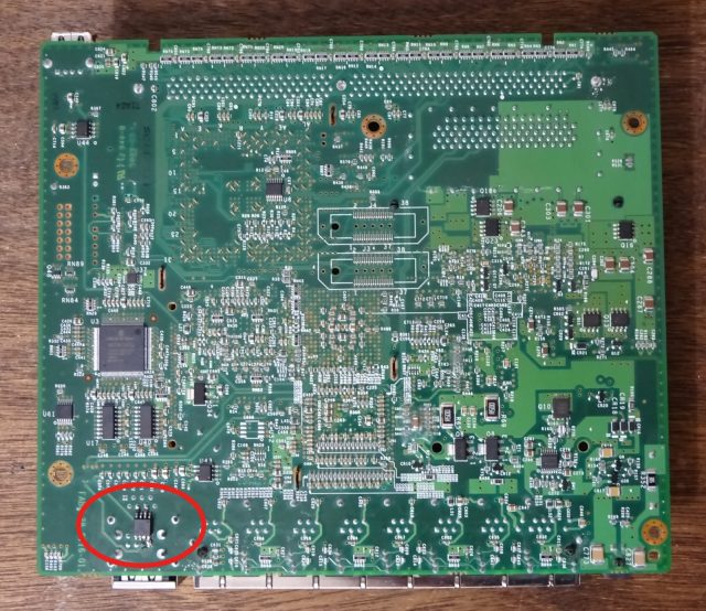 The bottom side of a Cisco ASA 5505 firewall motherboard, with the red oval marking the 5-millimeter-squared chip that Elkins added.