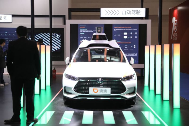 Image of a person standing near a vehicle with autonomous driving sensors on its roof.