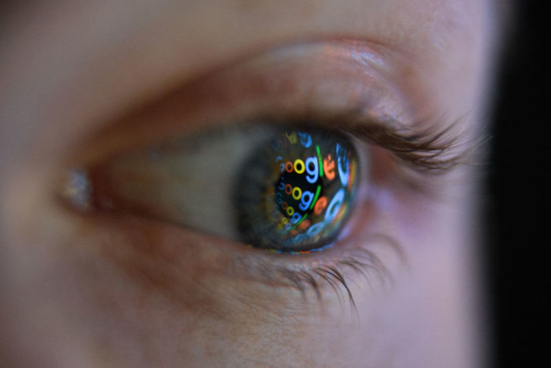 Photo illustration showing the Google logo reflected on the eye of a young man.