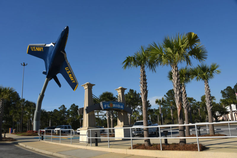 A decommissioned fighter jet is held up by a metal beam over a highway rest stop.