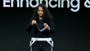 A woman shows off VR devices while onstage.