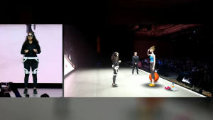 A woman shows off VR devices while onstage.