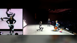 A woman shows off VR devices while onstage.