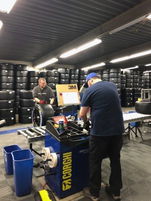 Two men mount racing tires in a garage