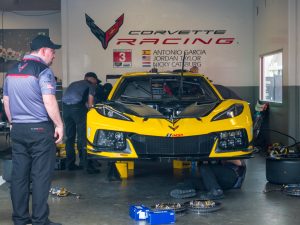 A yellow race car being worked on in a garage.