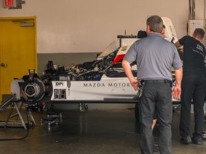 A white Mazda racing prototype in the garage.