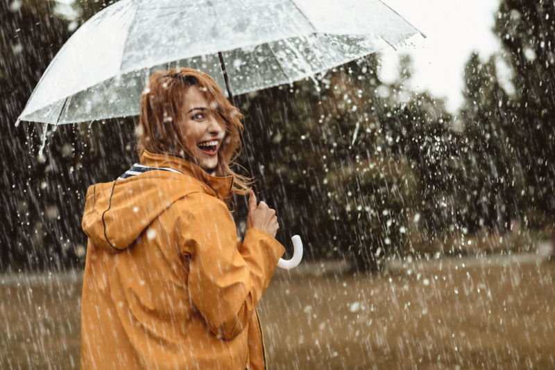 Cheerful pretty girl holding umbrella while strolling outside.