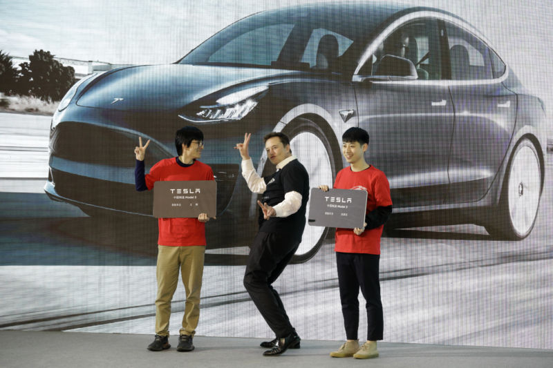 An otherwise serious man performs a silly dance in front of a large video screen.