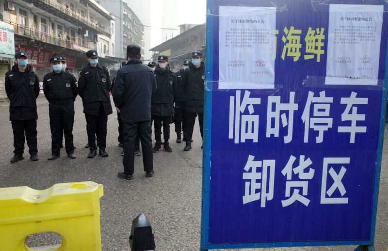 People in breathing masks stand on the pavement and take orders.