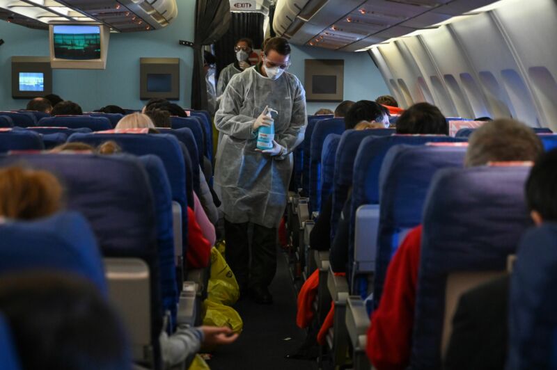 A crew member of an evacuation flight of French citizens from Wuhan gives passengers disinfectant during the flight to France on February 1, 2020, as they are repatriated from the coronavirus hot zone.