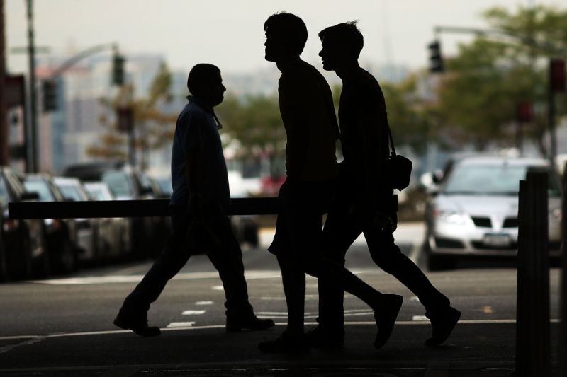 Three pedestrians cross a road in New York City