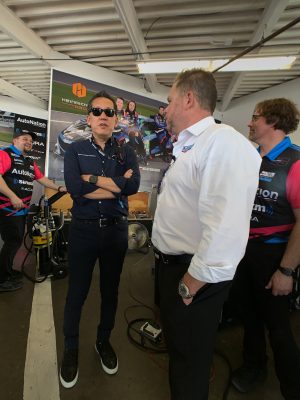 four men stand in a racing garage