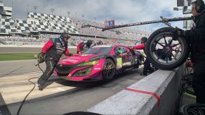 A pink race car gets its tires changed