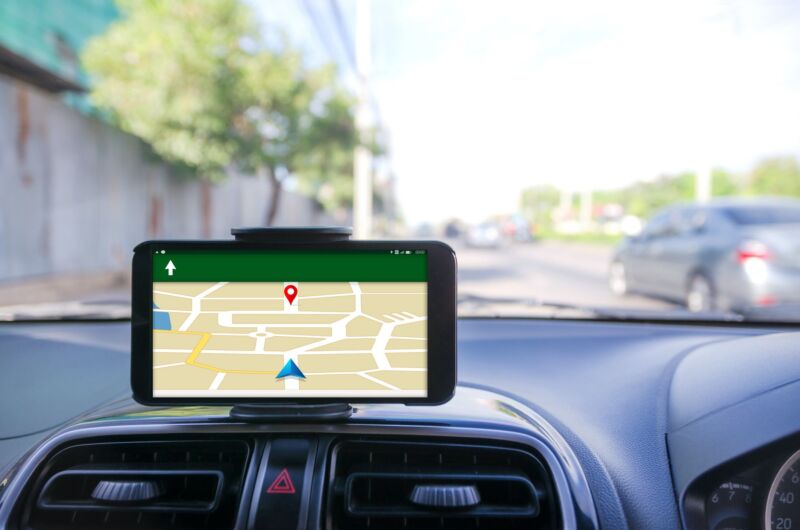 A cell phone displays a map and directions while mounted on a car dashboard.