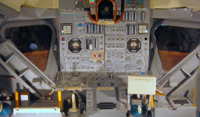 Inside an Apollo lunar module mock-up. The Abort and Abort Stage pushbuttons are outlined in caution tape on the left (CDR) side of the central instrument panel.