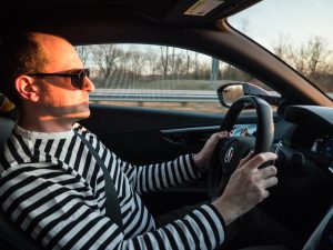 A man in a striped top drives a car