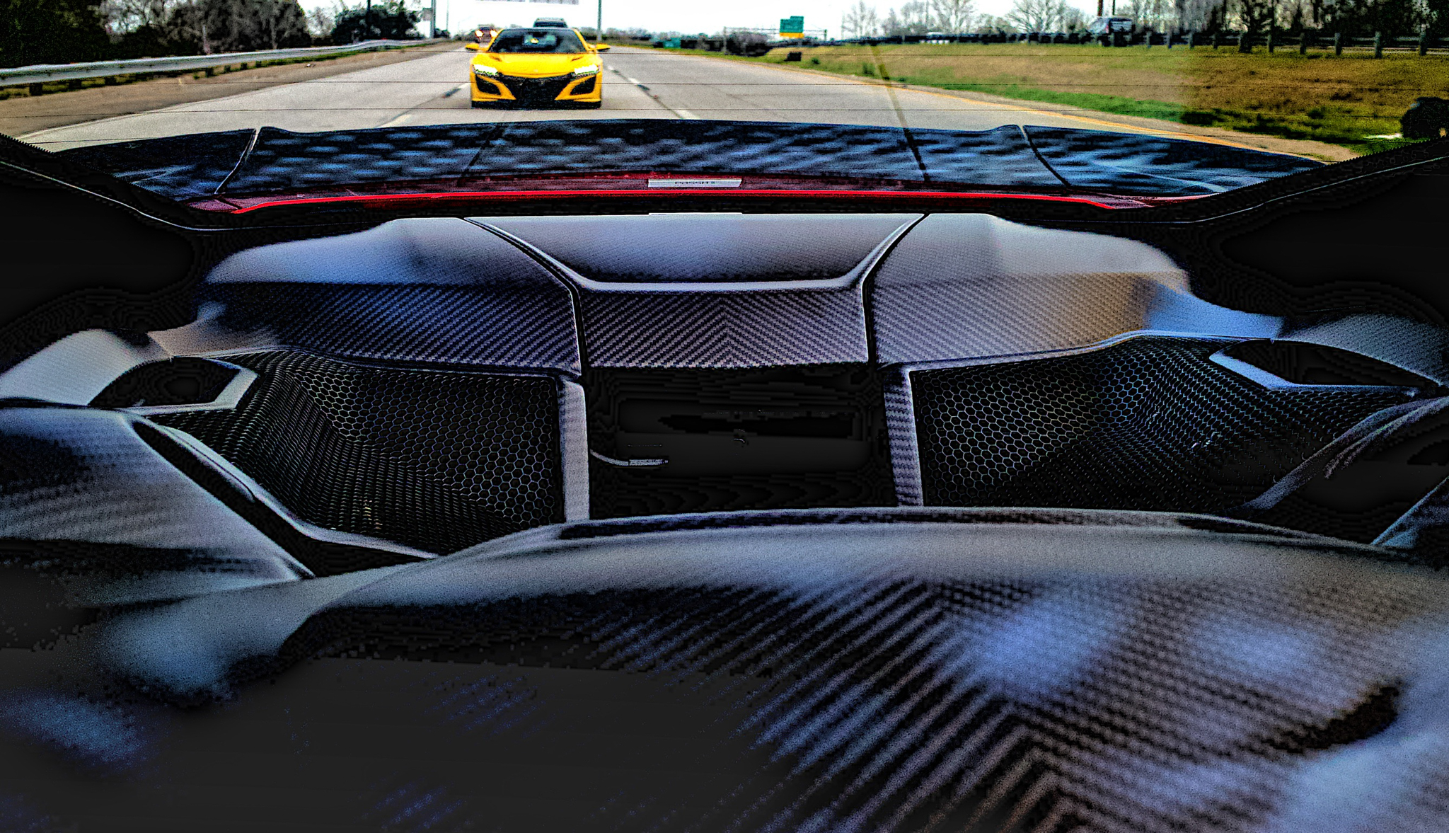 A yellow NSX seen from the rear window of a red NSX