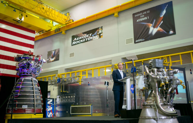 A man speaks from a podium in a space vehicle factory.