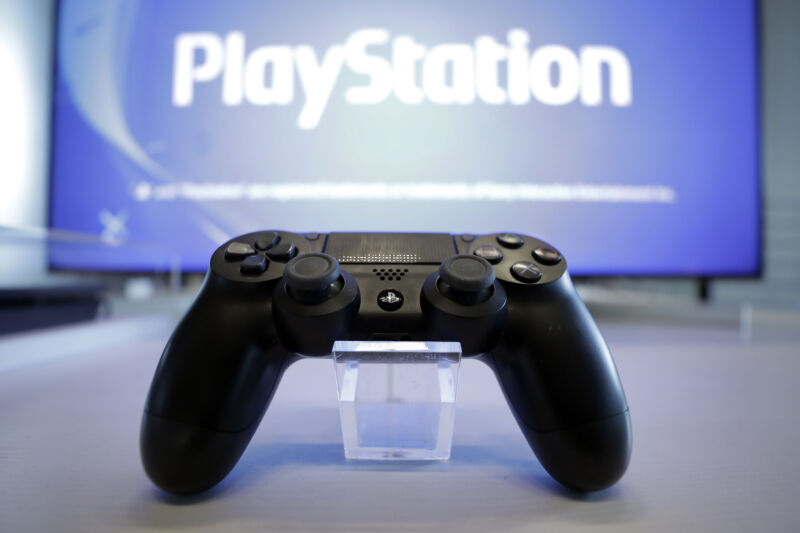 Photograph of a video game controller next to a monitor that reads Playstation.
