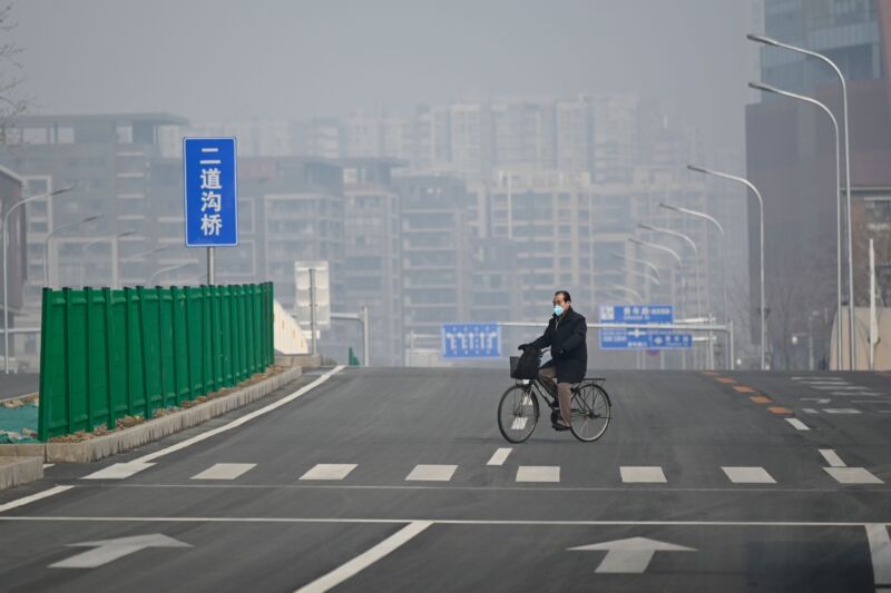 A man wearing a face mask rides his bicycle along an empty street in Beijing on February 12, 2020. 