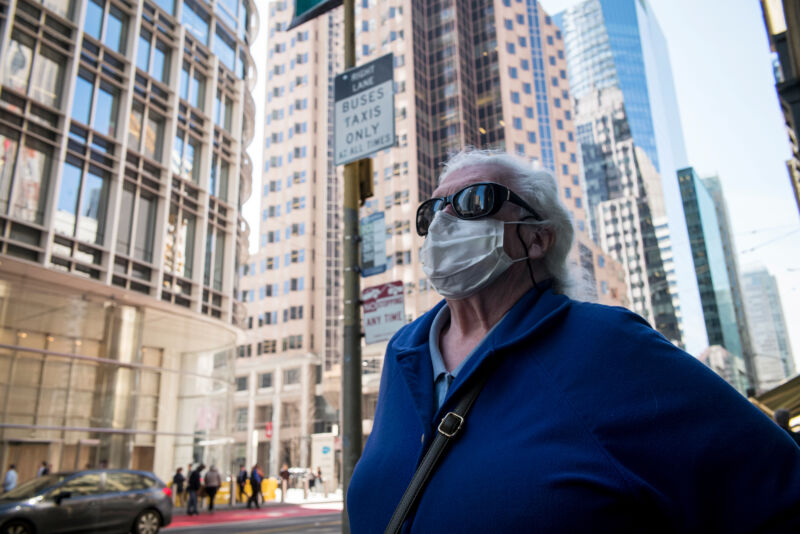 A pedestrian wearing a protective mask stands on Mission Street in San Francisco, California, on Thursday, Feb. 27, 2020. California is monitoring 8,400 people for signs of the virus after they traveled to Asia.