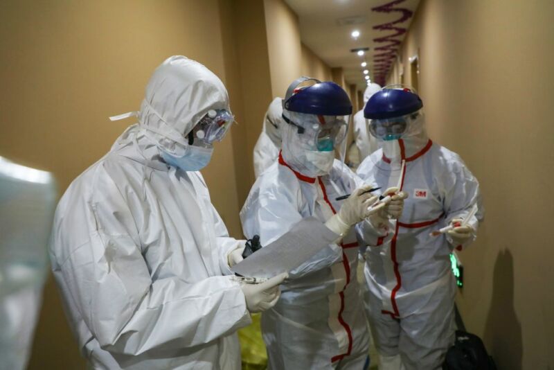 This photo taken on February 4, 2020, shows a medical staff member (C) marking a test tube containing samples taken from a person to be tested for the new coronavirus at a quarantine zone in Wuhan, the epicenter of the outbreak, in China's central Hubei province. 