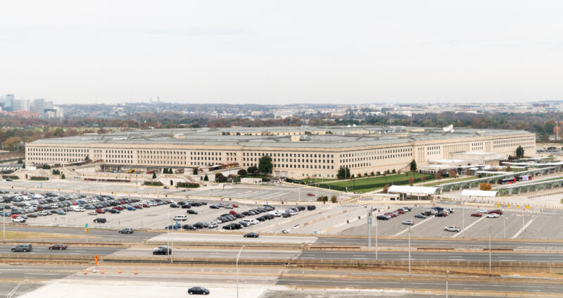 Sprawling Concrete Building Surrounded By Enormous Parking Lot.